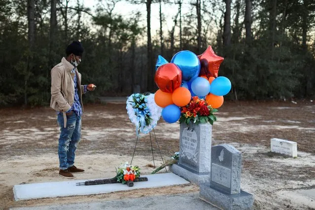 A man stands holding a candle next to the grave of Ahmaud Arbery, a Black man who was chased down and shot dead as he jogged through his Georgia neighborhood, during a candlelight vigil to mark the one year anniversary of his death, at New Springfield Baptist Church in Waynesboro, Georgia, February 23, 2021. (Photo by Dustin Chambers/Reuters)