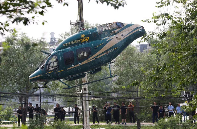 A crane lifts a helicopter after it crashed in Beijing, China, July 30, 2018. (Photo by Thomas Peter/Reuters)