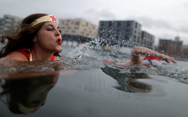 A winter swimmer dressed as a super-hero enjoys a Christmas bath in the 5 degrees Celsius (41 degrees Fahrenheit) water of the Canal de l'Ourq in Pantin outside Paris, France, December 24, 2016. (Photo by Christian Hartmann/Reuters)
