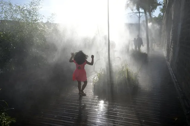 A kid walks along fresh water fogger system along the Seine river, as Europe is under an unusually extreme heat wave, in Paris, France, Tuesday, August 2, 2022. (Photo by Francois Mori/AP Photo)