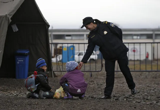 A police officer talks with migrant children as migrants and refugees are registered by the authorities before continuing their train journey to western Europe at a refugee transit camp in Slavonski Brod, Croatia, February 10, 2016. (Photo by Darrin Zammit Lupi/Reuters)