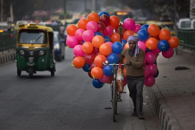 A balloon vendor pushes his bike through a street in New Delhi, India, Friday, February 12, 2016. On Monday, India said its economy grew 7.3 percent in the last three months of 2015, a rate of expansion that puts the South Asian nation ahead of China's 6.8 percent growth during the same period. (Photo by Bernat Armangue/AP Photo)