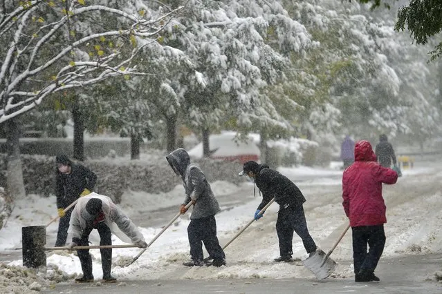 People shovel a street during snowfall in Shenyang, in China's northeastern Liaoning province on November 6, 2023. (Photo by AFP Photo/China Stringer Network)