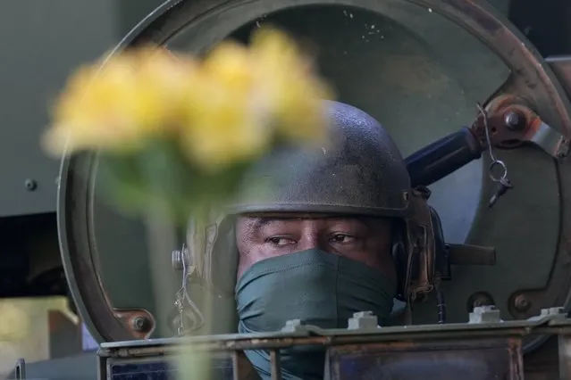 A soldier in a parked military vehicle is offered yellow flowers by opposition protesters outside Navy headquarters in Brasilia, Brazil, Tuesday, August 10, 2021, after parading by the Planalto presidential palace. A military convoy paraded by the palace on Tuesday, the day of a key congressional vote on a constitutional reform proposal supported by President Jair Bolsonaro that would add printed receipts to some of the nation’s electronic ballot boxes. (Photo by Eraldo Peres/AP Photo)