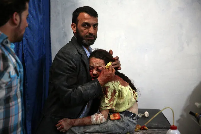 A handout image provided by the World Press Photo (WPP) organization on 18 February 2016 shows a picture by photographer Abd Doumany that won Second Prize Stories in the General News Category of the 59th annual World Press Photo Contest, it was announced by the WPP Foundation in Amsterdam, The Netherlands on 18 February 2016. The picture shows a wounded Syrian girl holding on to a relative as she awaits treatment by doctors at a makeshift hospital in the rebel-held area of Douma, east of the capital Damascus, following reported air strikes on the city on 11 May 2015. (Photo by Abd Doumany/World Press Photo Contest/EPA)