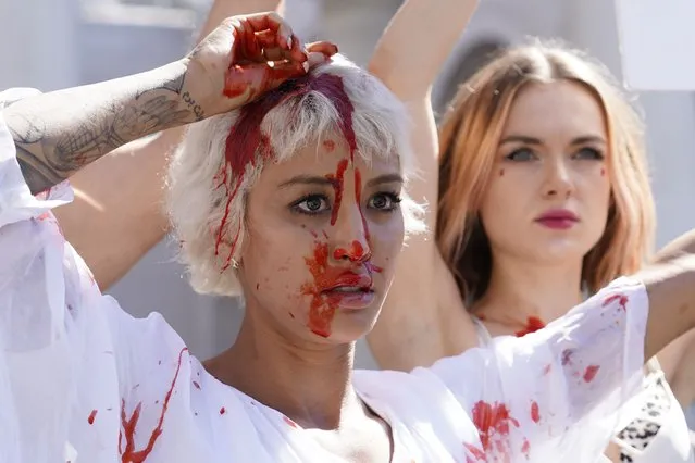 Iranian American artist Samy Rose, left, drops theatrical blood on her head after Yadviga Krasovskaya from Belarus, background, cut her hair during a rally in solidarity with women in Iran, after 22-year-old woman Mahsa Amini died in police custody, in downtown Los Angeles on Saturday, October 1, 2022. As anti-government protests roil cities and towns in Iran for a fourth week, sparked by the death of Amini, tens of thousands of Iranians living abroad have marched on the streets of Europe, North America and beyond in support of what many believe to be a watershed moment for their home country. (Photo by Damian Dovarganes/AP Photo)