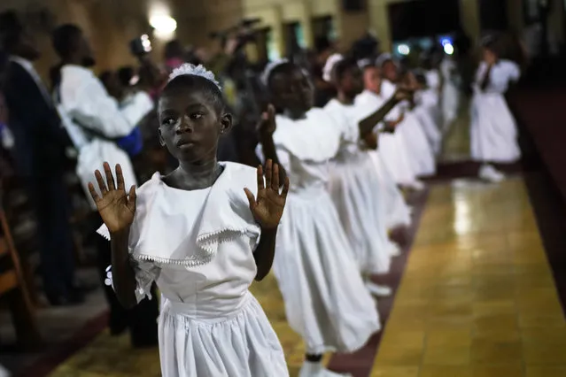 Congolese children dance before Msg. Fridolin Ambongo, the the newly appointed Archibishop of Kinshasa, delivers the homily during an early midnight mass at the Notre Dame du Congo Cathedral in Kinshasa, Congo, Monday December 24, 2018. Ambobgo said that Congolese people must embrace non-violence to make it through Dec. 30th elections. He warned that “The publication of results that would not reflect the will of the people as expressed in the ballot boxes would mean the annihilation of peace in our country”. (Photo by Jerome Delay/AP Photo)