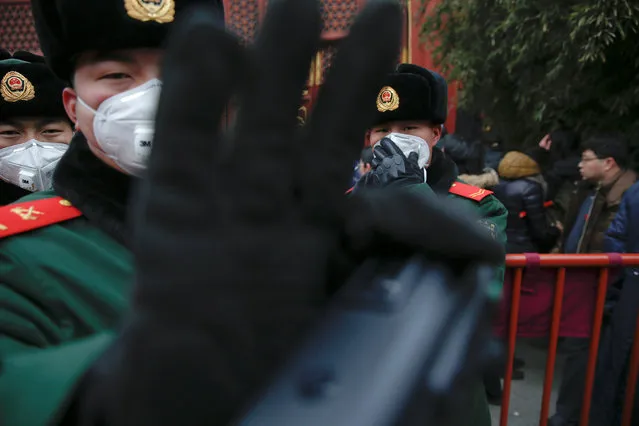 Paramilitary policemen providing security gesture towards a reporter as people gather at Yonghegong Lama Temple to burn incense and pray for good fortune on the first day of the Lunar New Year of the Rooster in Beijing, China January 28, 2017. (Photo by Damir Sagolj/Reuters)