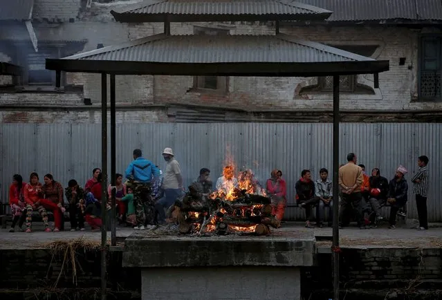 Relatives sit next to the funeral pyre of a victim of Saturday's earthquake along a river in Kathmandu, Nepal, April 27, 2015. (Photo by Danish Siddiqui/Reuters)