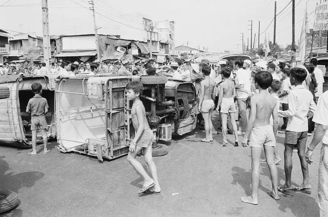 Saigon youngsters mill around overturned three wheeled minibuses during a demonstration by the vehicles drivers protesting various economic issues. The protest was one of two which tock place, March 25, 1975 in the South Vietnamese capital Saigon. (Photo by AP Photo)