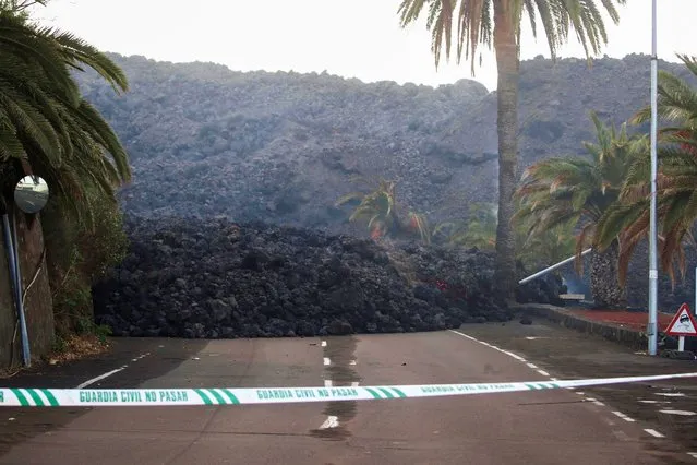 A Spanish Civil Guard tape is seen along a road blocked by lava spewed from the Cumbre Vieja volcano in La Laguna, as it continues to erupt on the Canary Island of La Palma, Spain, October 14, 2021. (Photo by Sergio Perez/Reuters)