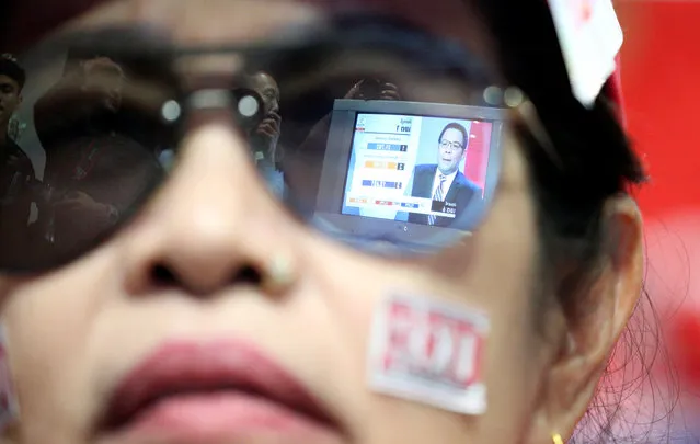 Live results are reflected in glasses of a supporter of Pheu Thai Party during the general election in Bangkok, Thailand, March 24, 2019. (Photo by Athit Perawongmetha/Reuters)