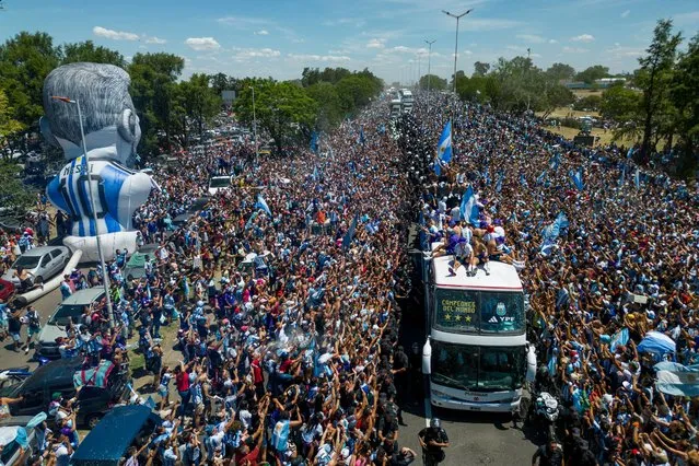 Argentina's players celebrate on board a bus with a sign reading “World Champions” with supporters after winning the Qatar 2022 World Cup tournament as they tour through Buenos Aires' downtown on December 20, 2022. Millions of ecstatic fans are expected to cheer on their heroes as Argentina's World Cup winners led by captain Lionel Messi began their open-top bus parade of the capital Buenos Aires on Tuesday following their sensational victory over France. (Photo by Tomas Cuesta/AFP Photo)