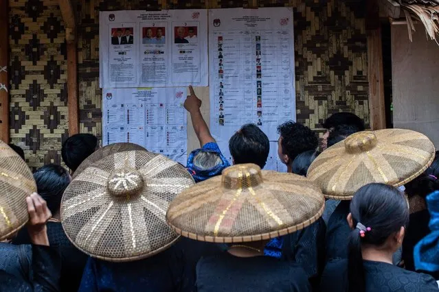 Members of the indigenous Baduy tribe check the candidates list at a polling station before they cast their ballots and vote in Indonesia's presidential and legislative elections in Kanekes Village, Lebak, Banten province on February 14, 2024. Voting began on February 14 in Indonesia's presidential, national and provincial elections at more than 800,000 polling stations across the country, with nearly 205 million people eligible to cast their ballot. (Photo by Aditya Aji/AFP Photo)