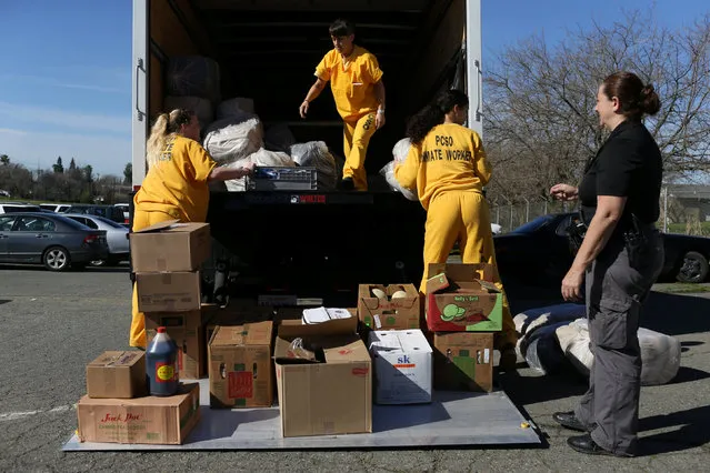 Roseville Jail inmates Tanya Flint (L), Canace Bailey (2nd L) and Jasmine Hess (2nd R) deliver donated food and blankets under the supervision of Placer County Correctional Officer Christina Roberts at the Salvation Army relief center at the Placer County Fairgrounds in Roseville, California, after an evacuation was ordered for communities downstream from the dam in Oroville, California, U.S. February 14, 2017. (Photo by Beck Diefenbach/Reuters)