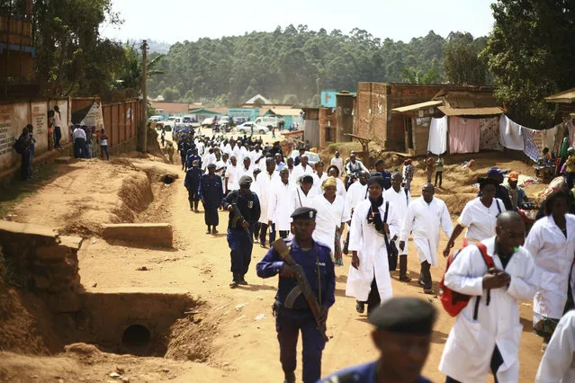 Doctors and health workers march in the Eastern Congo town of Butembo on Wednesday April 24, 2019, after attackers last week shot and killed an epidemiologist from Cameroon who was working for the World Health Organization. Doctors at the epicenter of Congo's Ebola's crisis are threatening to go on strike indefinitely if health workers are attacked again. (Photo by Al-hadji Kudra Maliro/AP Photo)