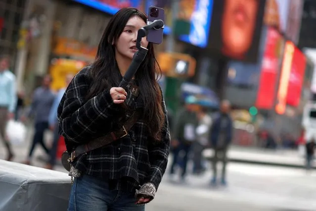 A woman makes a video with a mobile phone to post on TikTok as she stands in Times Square in New York City, New York, U.S., March 13, 2024. (Photo by Mike Segar/Reuters)
