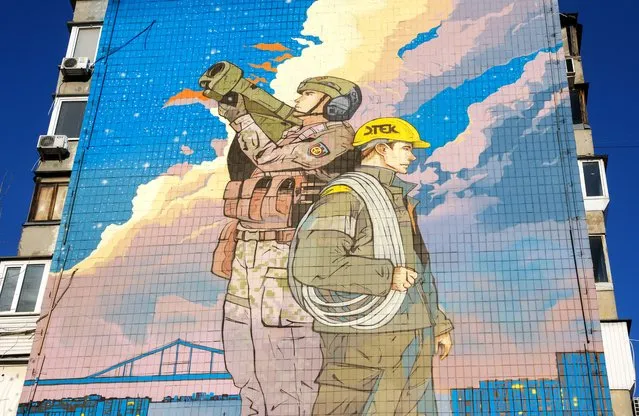 A view of a mural dedicated to Ukrainian air defense forces and energy workers in Kyiv (Kiev), Ukraine, 30 November 2023, amid the Russian invasion. The mural, created by Ukrainian artists Andrii Kovtun and Anton Kudryashov was unveiled on 30 November. Symbolically named “Defenders of Light”, it depicts a Ukrainian soldier guarding the skies from aerial threats and an energy worker ready to repair power grids in case of damage. During the winter season of 2022-2023, Russia launched missile and drone strikes targeting energy infrastructure across Ukraine. Russian troops entered Ukraine on 24 February 2022 starting a conflict that has provoked destruction and a humanitarian crisis. (Photo by Sergey Dolzhenko/EPA/EFE)