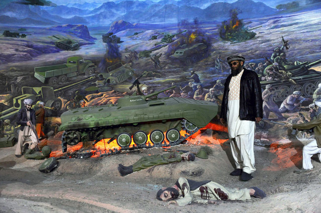 Museum assistant Sheikh Abdullah stands at a display of burning Soviet tanks in the Jihad Museum, on February 15, 2014. (Photo by Aref Karimi/AFP Photo via The Atlantic)