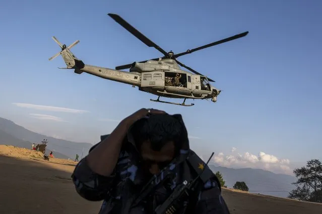 A Nepalese military personnel takes cover as an UH-1Y, belonging to the U.S. military, takes off after Tuesday's earthquake at Charikot Village, in Dolakha, Nepal, May 14, 2015. Picture taken May 14, 2015. (Photo by Athit Perawongmetha/Reuters)