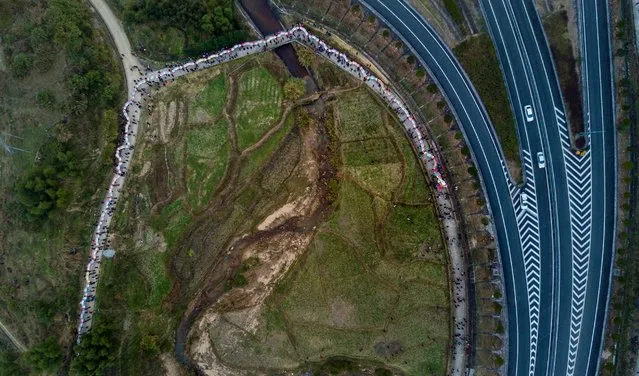 This picture taken on February 11, 2017 shows villagers parading a dragon next to a highway in the fields near Gutian village, Liancheng county of China's eastern Fujian province. Dragons several hundred metres long snake their way down pastoral roads and through country hamlets, part of centuries-old Chinese folk celebrations for a mythical creature revered as a blessing. The visually striking festival is among a range of colourful traditional observances unique to eastern Fujian province and its Hakka people and held each year in conjunction with the Lantern Festival, which fell this year on February 11. (Photo by Johannes Eisele/AFP Photo)