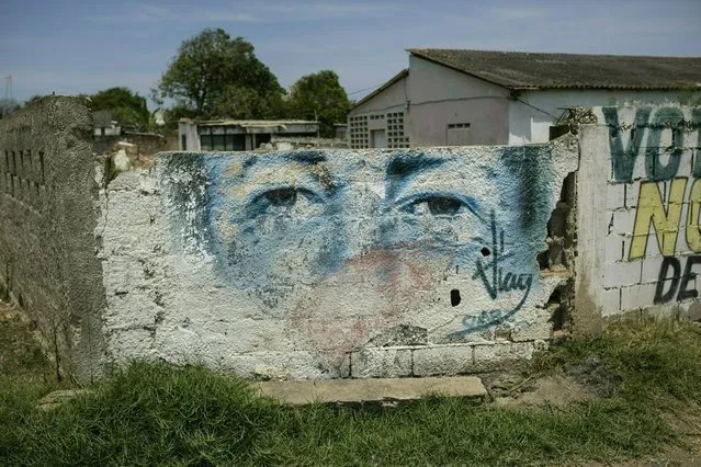 An eroded mural of Venezuela's late President Hugo Chavez covers a wall in Machurucuto, Venezuela, Sunday, May 5, 2019. For many town residents, their only contact with the Cubans is at a hospital in a nearby city where Cuban doctors treat them for free, albeit with alarmingly scant medical supplies. (Photo by Rodrigo Abd/AP Photo)