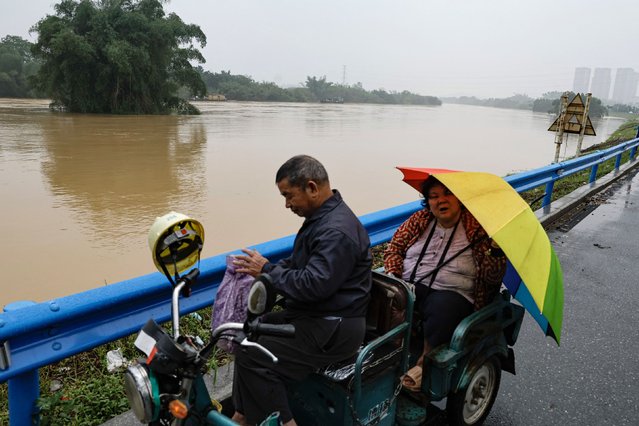 Residents ride on a scooter near a flooded river, following heavy rainfall in Qingyuan, Guangdong province, China on April 22, 2024. (Photo by Tingshu Wang/Reuters)