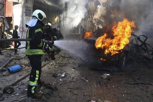 This photo provided by the Syrian Civil Defense White Helmets, which has been authenticated based on its contents and other AP reporting, shows a Syrian White Helmet civil defense worker, extinguishes flames rising from a burning car, in the town of Afrin, north of Aleppo, Thursday, January 20, 2022. The rocket attack on Afrin, controlled by Turkey-backed opposition fighters, killed several civilians and wounded over a dozen people on Thursday, Syrian rescuers and a war monitor said. Both blamed U.S-backed Syrian Kurdish forces for the attack. (Photo by Syrian Civil Defense White Helmets via AP Photo)