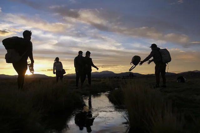 Migrants cross a stream after crossing into Chile from Bolivia, near Colchane, Chile, Thursday, December 9, 2021. (Photo by Matias Delacroix/AP Photo)