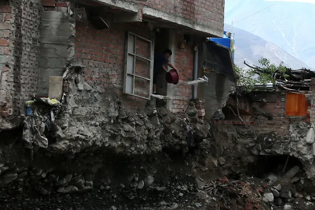 A man throws water outside his house after a landslide and flood in Chosica, Peru on March 16, 2017. (Photo by Guadalupe Pardo/Reuters)