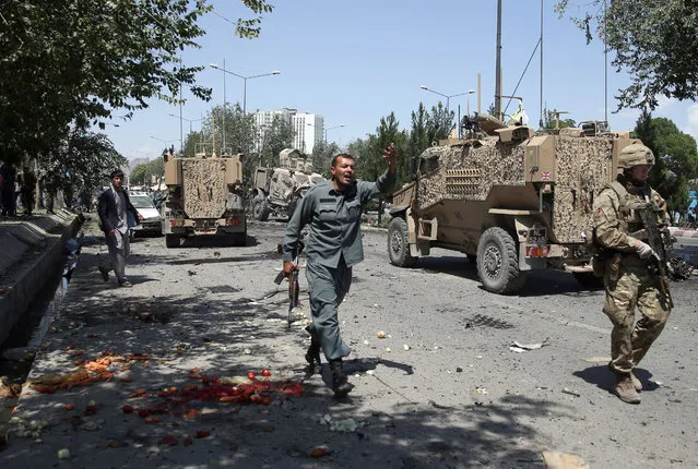 An Afghan policeman shouts at the site of a suicide attack on a NATO convoy in Kabul, Afghanistan, Tuesday, June 30, 2015. (Photo by Massoud Hossaini/AP Photo)