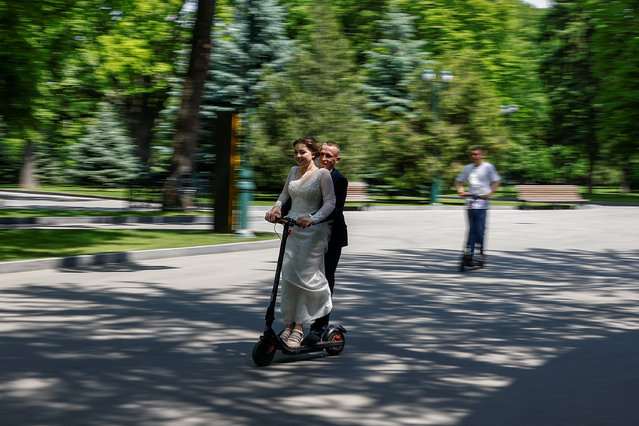 Newly married couple Oleksandr and Diana ride an electric scooter, amid Russia's attack on Ukraine, in central Kharkiv, Ukraine on May 21, 2024. (Photo by Valentyn Ogirenko/Reuters)