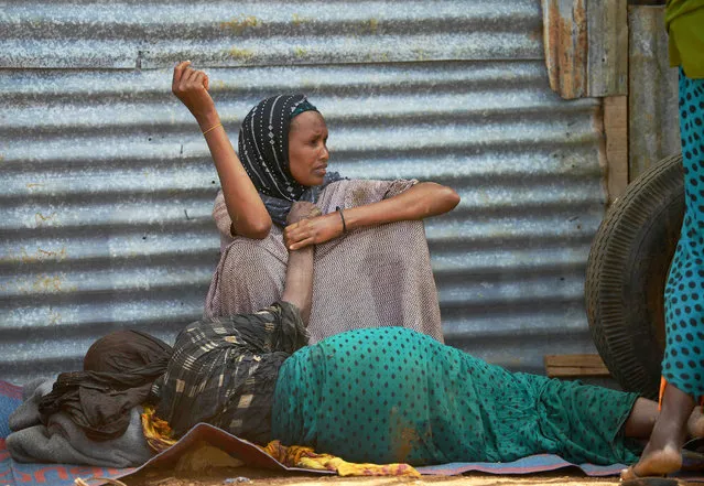 An elderly woman weakened by hunger lies on the ground as her daughter watches over  her at a camp for the internally displaced on the outskirts of Baidoa town, the capital of Bay region of south-western Somalia where people escaping the impact drought from areas cut-off to emergency aid by al-Shabaab Islamists continue to arrive daily on March 15, 2017. (Photo by Tony Karumba/AFP Photo)