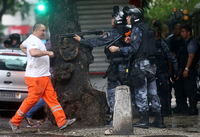 Police hold their weapons during clashes with residents of the Pavao-Pavaozinho slum during a protest following the funeral of dancer Douglas Rafael da Silva, who was shot and killed, on April 24, 2014 in Rio de Janeiro, Brazil. Da Silva's body was discovered in the pacified Pavao-Pavaozinho community, just blocks from Copacabana Beach, on April 22. (Photo by Mario Tama/Getty Images)