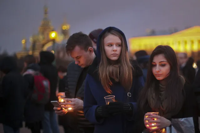 Young people hold candles as they gather to honor the memory of the victims of subway bombing on Marsovo Polye in St. Petersburg, Russia, Wednesday, April 5, 2017. A bomb blast tore through a subway train under Russia's second-largest city on Monday, killing several people and wounding more. (Photo by Yevgeny Kurskov/AP Photo)