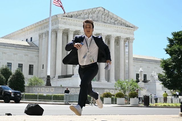 A journalist runs across the US Supreme Court plaza carrying an opinion to a news correspondent as the court handed down decisions  on July 1, 2024, in Washington, DC. Donald Trump on Monday hailed a “big win” for democracy after the US Supreme Court ruled that presidents have presumptive immunity for official acts – a decision set to delay his trial for conspiring to overturn his 2020 election loss. (Photo by Drew Angerer/AFP Photo)