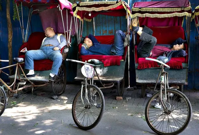 Chinese trishaw drivers take nap while waiting for customers at a hutong alley near the drum tower, a tourist spot in Beijing, China Wednesday, May 7, 2014. (Photo by Andy Wong/AP Photo)