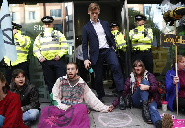 A man walks out of the Home office past climate change protesters on the second day of ongoing protests in London, Tuesday, October 8, 2019. Police are reporting they have arrested more than 300 people at the start of two weeks of protests as the Extinction Rebellion group attempts to draw attention to global warming. (Photo by Alastair Grant/AP Photo)