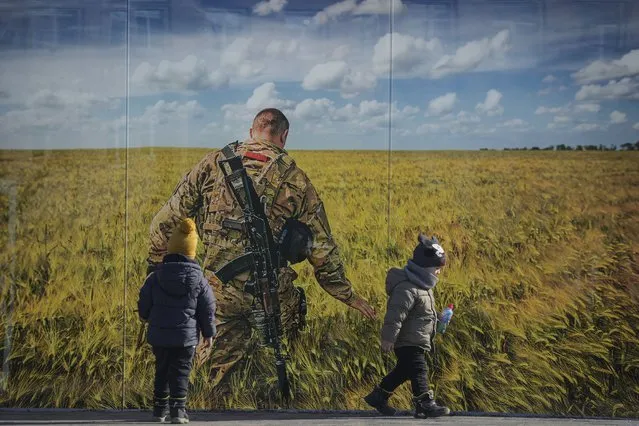 Children play by a large print at a photographic memorial for those killed in the confrontation between Ukraine's military and the pro-Russia separatist forces in Sievierodonetsk, the Luhansk region, eastern Ukraine, Wednesday, February 23, 2022. The head of Ukraine's National Security and Defense Council called for a nationwide state of emergency – subject to parliamentary approval. (Photo by Vadim Ghirda/AP Photo)