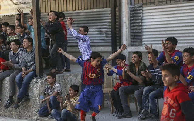 A photograph made available on 18 May 2016 shows substitutes reacting after their team-mates scored a goal during the first school football tournament, in the rebel-held city of Douma, Syria, 20 April 2016. Twelve teams took part in the first school football tournament that started on 16 April 2016. Ten days later the tournament was postponed after the fragile ceasefire between the government and rebel groups was breached by a wave of violence and several parts of Eastern Ghouta were targeted by government shelling. The final match was held on 14 May and al-Hekma school team snatched the title after beating al-Rowad school. (Photo by Mohammed Badra/EPA)