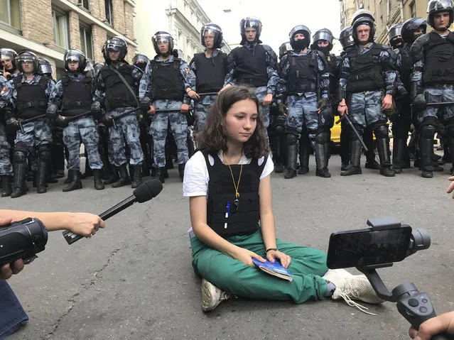 In this photo taken on Saturday, July 27, 2019, member of protester's group “Bessrochka” Olga Misik sits in front police officers during an unsanctioned rally in the center of Moscow, Russia. Bessrochka's best-known member 17-year-old Olga Misik is currently under arrest. (Photo by Alexei Abanin via AP Photo)
