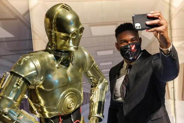 A person takes a selfie with a life-size figure of C-3PO at “The Fans Strike Back: The Largest Star Wars Fan Exhibition” in Manhattan, New York City, U.S., March 24, 2022. (Photo by Andrew Kelly/Reuters)