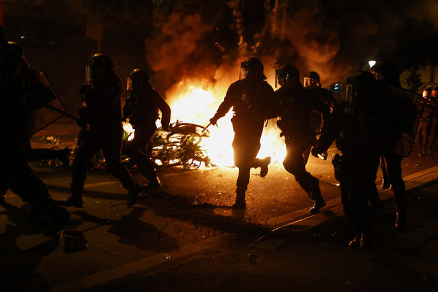 French CRS riot police run past burning bicycles during clashes with demonstrators following partial results in the second round of the early French parliamentary elections, at the Place de la Republique in Paris, France, on July 7, 2024. (Photo by Abdul Saboor/Reuters)