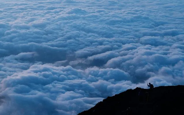 In this Tuesday, August 27, 2019, file photo, a climber stops to take pictures of clouds while climbing towards the summit of Mount Fuji to watch the sunrise, in Japan. (Photo by Jae C. Hong/AP Photo/File)