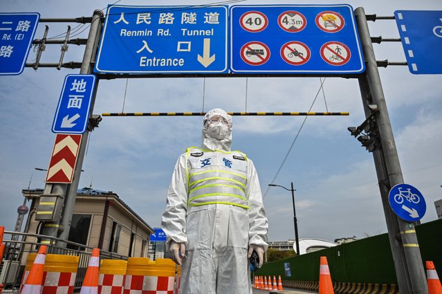 A transit officer, wearing a protective gear, controls access to a tunnel in the direction of Pudong district in lockdown as a measure against the Covid-19 coronavirus, in Shanghai on March 28, 2022. Millions of people in China's financial hub were confined to their homes on March 28 as the eastern half of Shanghai went into lockdown to curb the nation's biggest Covid outbreak. (Photo by Hector Retamal/AFP Photo)
