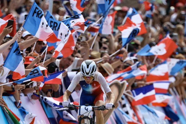 France's Pauline Ferrand Prevot cycles past spectators waving French flags as she competes in the women's cross-country mountain biking event during the Paris 2024 Olympic Games in Elancourt Hill venue in Elancourt, on July 28, 2024. (Photo by Emmanuel Dunand/AFP Photo)