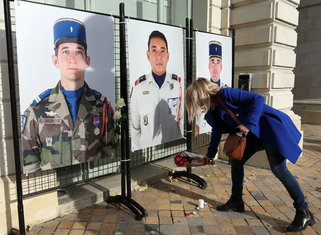 A woman lays flowers under portraits of French soldiers, Alex Morisse, left, Romain Salles de Saint Paul, center, and Nicolas Regard at the town hall of Pau, southwestern France, Wednesday, November 27, 2019. Two helicopters collided on a moonless night and killed 13 French soldiers fighting Islamic State group-linked extremists in Mali, France said Tuesday, mourning its highest military death toll in nearly four decades. (Photo by Bob Edme/AP Photo)