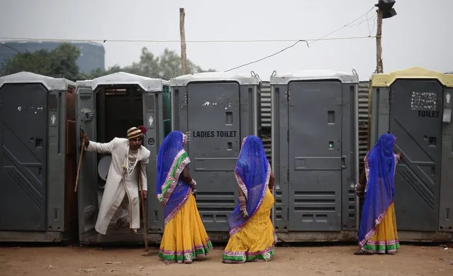 A groom comes out from a toilet as brides stand at the venue for a mass wedding ceremony at Ramlila ground in New Delhi June 15, 2014. A total of 92 physically challenged couples of all religions from across India took their wedding vows on Sunday during the mass wedding ceremony organised by a non-governmental organisation (NGO), organisers said. (Photo by Adnan Abidi/Reuters)
