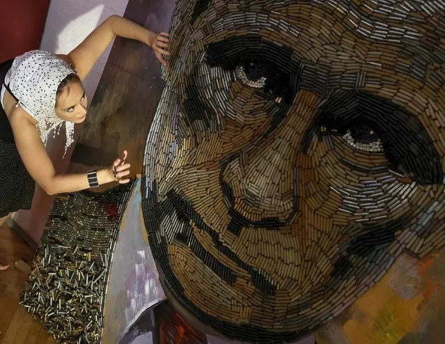 Ukrainian artist Dariya Marchenko works on a portrait of Russian President Vladimir Putin named “The Face of War” which is made out of 5,000 cartridges brought from the frontline in eastern Ukraine, in Kiev, July 23, 2015. The portrait will be presented along with a novel which will tell personal stories of six people involved in this project including Daria's own story and stories of people who helped her to collect shells from the frontline. (Photo by Gleb Garanich/Reuters)