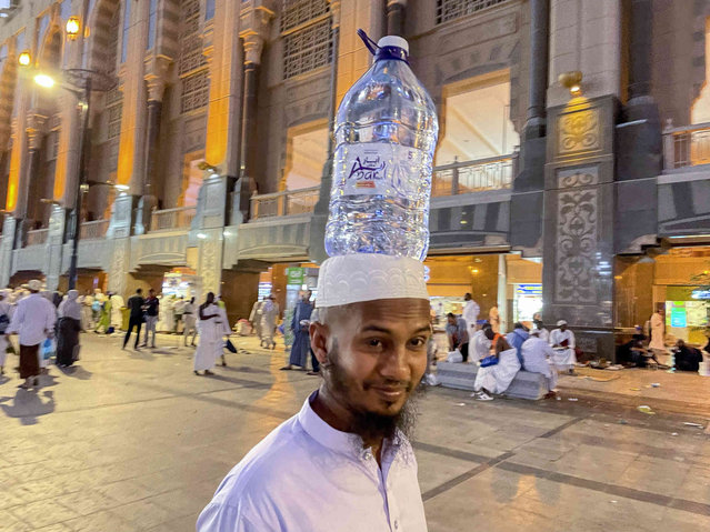 A Bengali pilgrim carries a water bottle over his head outside the Grand Mosque, during the annual hajj pilgrimage, in Mecca, Saudi Arabia, Sunday, June 25, 2023. Muslim pilgrims are converging on Saudi Arabia's holy city of Mecca for the largest hajj since the coronavirus pandemic severely curtailed access to one of Islam's five pillars. (Photo by Amr Nabil/AP Photo)